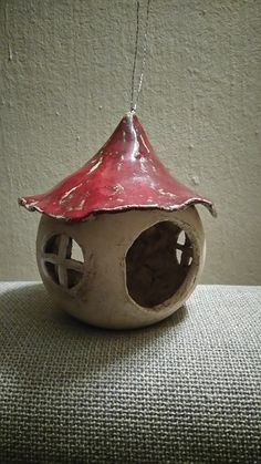 a small birdhouse with a red roof on top of a table next to a wall