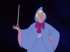 an old woman in costume holding a wand and pointing to the side with her hand