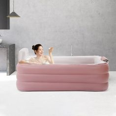 a woman is sitting in an inflatable bathtub and waving to the side