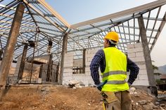 a construction worker standing in front of a building under construction with his back to the camera