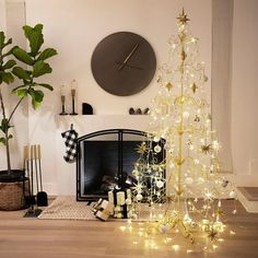 a decorated christmas tree sitting in front of a fire place next to a wall clock