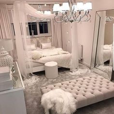 a bedroom with white furniture and chandelier hanging from the ceiling in front of a mirror