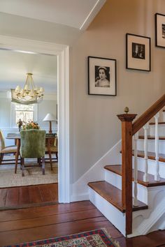 a staircase with pictures on the wall and wooden steps leading up to a dining room table