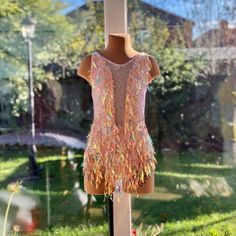 a mannequin wearing a dress made out of feathers on display in front of a window