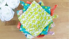 a close up of a bunch of cloths on a wooden surface with flowers in the background