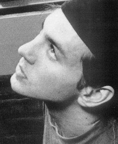 black and white photograph of a man with ear buds on his ears looking out the window