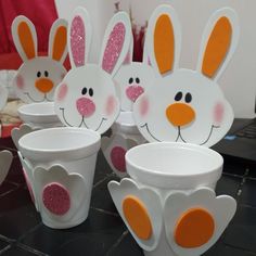 some white cups with orange and pink bunny ears on them sitting on a black table