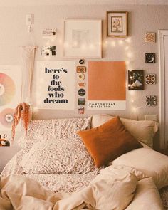 an unmade bed with lots of pillows and pictures on the wall next to it