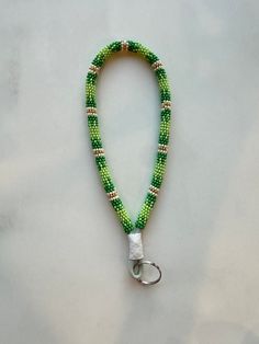 a green beaded lanyard with white beads and a key ring on a table