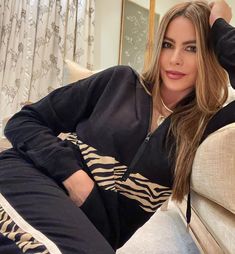 a woman sitting on top of a couch wearing black and white tracksuits with zebra print