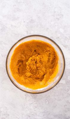 a bowl filled with orange colored food on top of a white counter