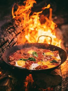 a skillet is cooking food over an open fire