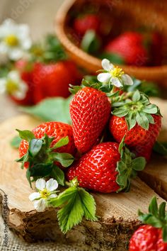 fresh strawberries with flowers and leaves on the wooden table, close - up photo