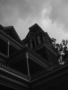 a black and white photo of an old building with a clock on the front porch