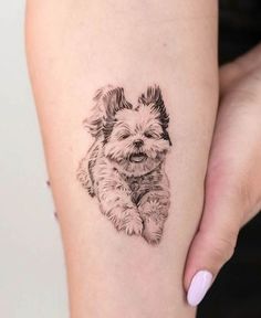 a small black and white dog tattoo on the right thigh, with an outline of a puppy