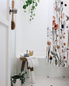 a bathroom with a shower curtain, potted plants and a stool in the corner