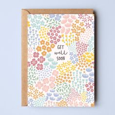 a card with the words get well soon surrounded by colorful flowers and leaves on a light blue background