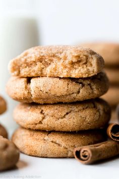 a stack of cookies and cinnamons next to a glass of milk