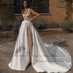 a woman standing in front of a brick building wearing a white dress with sheer cutouts