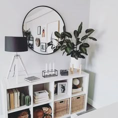 a white shelf with books and pictures on it in front of a round mirror that says explore