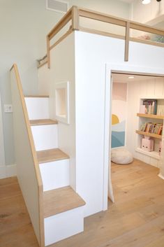 there is a staircase leading up to the loft bed in this small room with white walls and wood flooring