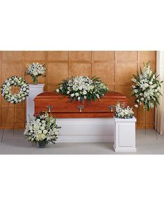 white flowers and greenery are arranged on the casket