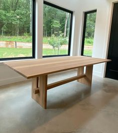 an empty room with large windows and a wooden table