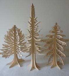 three wooden trees are standing next to each other on a white tablecloth covered surface