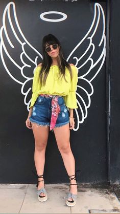 a woman standing in front of a wall with angel wings on it's back