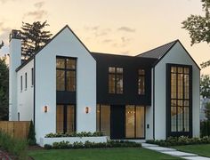 a white house with black trim and windows on the front lawn at sunset or dawn