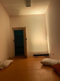 an empty room with two pillows on the floor and a door leading to another room