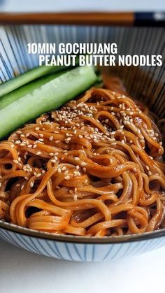 a bowl filled with noodles, cucumbers and sesame seeds