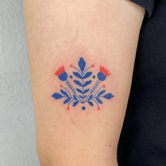 a blue and red flower tattoo on the right arm, it looks like something from another country