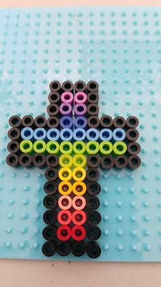 a cross made out of legos sitting on top of a blue surface with black and white circles