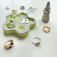 various rings and bracelets on a tray next to a bottle with a ring holder