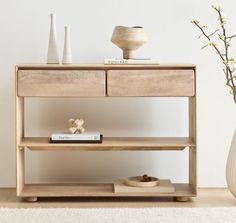 a white vase sitting on top of a wooden table next to a shelf filled with books