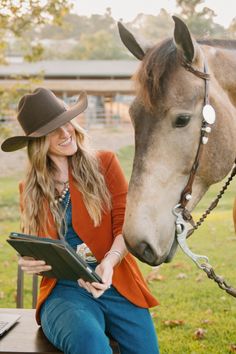 a woman sitting on a bench next to a horse wearing a cowboy hat and holding a clipboard