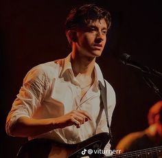 a man playing guitar while standing in front of a microphone