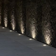 a man riding a skateboard down a sidewalk next to a wall with lights on it