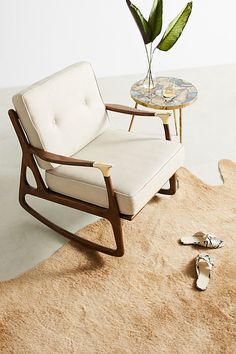 a white chair sitting on top of a rug next to a table with a potted plant