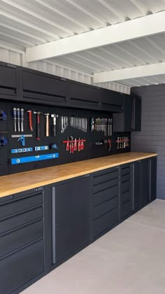 an organized garage with lots of tools hanging on the wall and cabinets in front of it