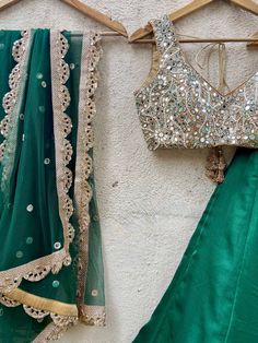 A three-piece emerald green mirror lehenga set from the Priti Sahni collection. This beautiful raw silk emerald green lehenga with a sari zari border detail is paired with a nude mirror blouse in pearl, and zardozi hand embroidery. This outfit is completed with an emerald green mirror work net dupatta with scalloped edging. Green Choli With Cutdana For Reception, Designer Green Choli With Sheer Dupatta, Green Cutdana Dupatta For Reception, Designer Green Lehenga With Sheer Dupatta, Green Raw Silk Anarkali Set With Gota Work, Pista Green Pre-draped Saree With Mirror Work For Navratri, Transitional Anarkali Green Lehenga, Green Raw Silk Anarkali Set For Reception, Designer Green Lehenga For Transitional Season