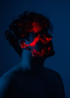 a man with red light painted on his face in the dark, looking at something