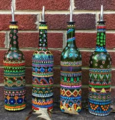 four colorful painted bottles lined up against a brick wall