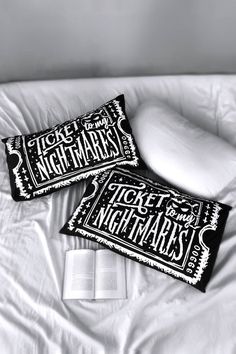 two pillow cases sitting on top of a bed with an open book next to them