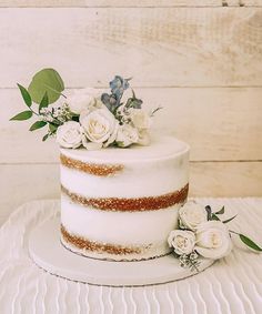 a white cake with flowers and greenery on top