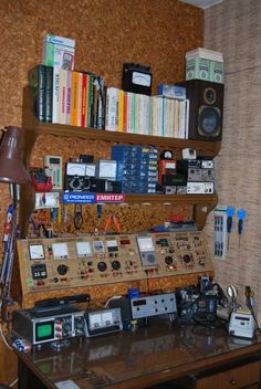 an old radio and other electronic equipment on a desk in front of a bookshelf