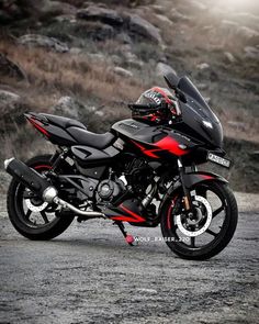 a red and black motorcycle parked on the side of a road