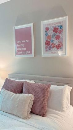 two framed pictures hang above a bed with white linens and pink pillows on it