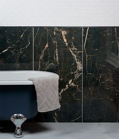 a bath tub sitting next to a black and white tiled wall